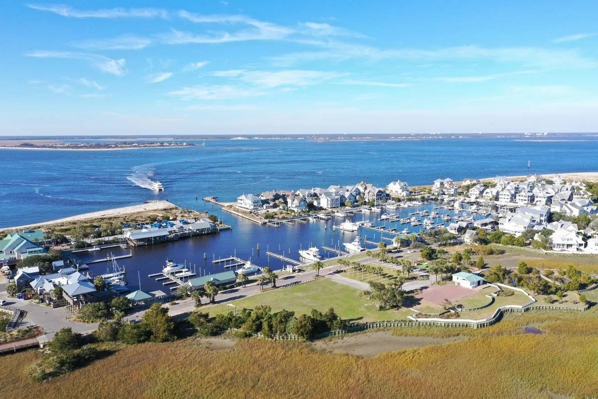 A wide view of the island’s marina with boats docked along a waterway, houses along the shore, and green spaces. The image captures an active, inviting scene ideal for exploration by golf cart, as mentioned in the section.