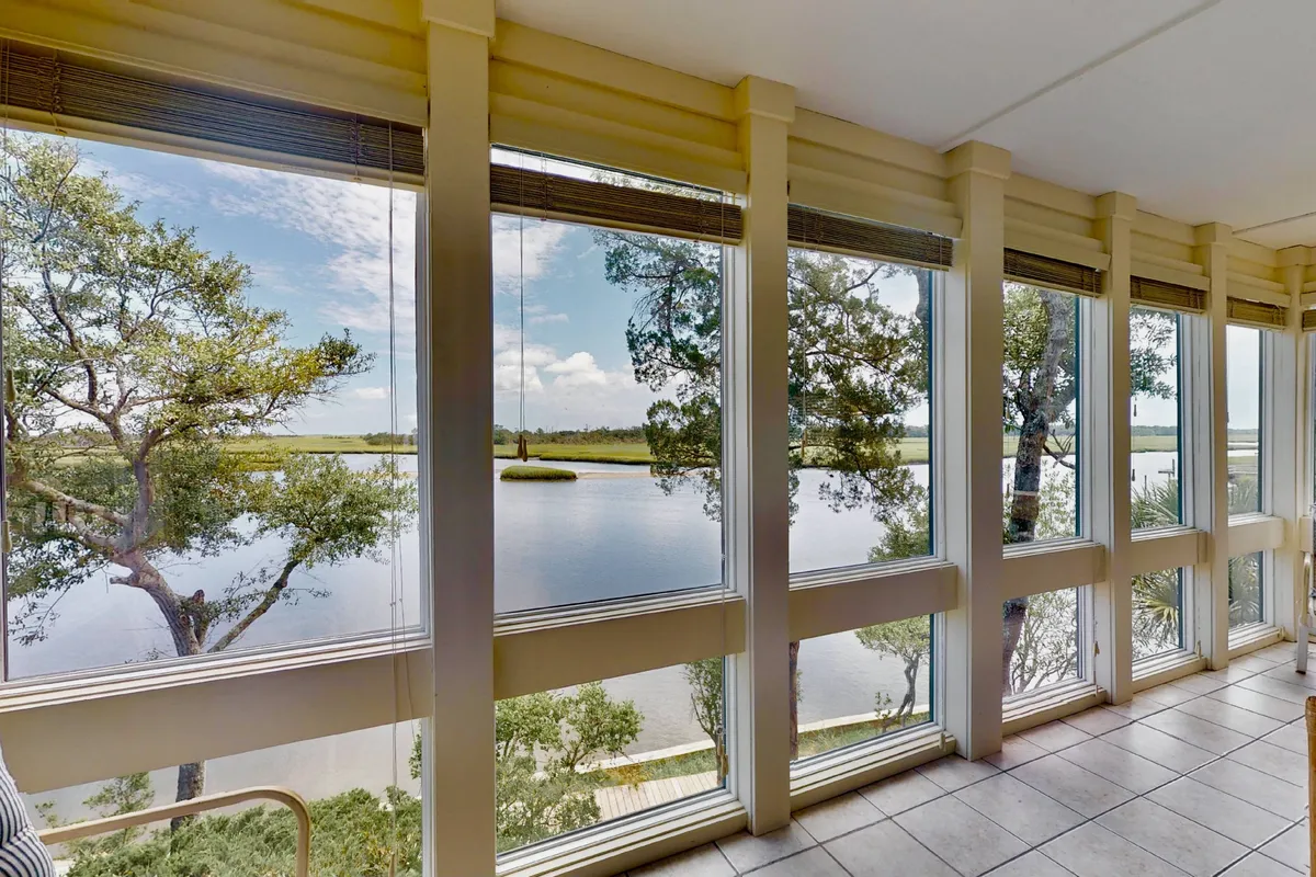 A serene sitting area defined by large windows overlooking calm waters and green treetops. The tranquil mood is perfect for watching wildlife, enjoying changing seasons, or basking in breathtaking sunsets. The room is arranged for peace and quiet, with natural light flooding in for a peaceful start or end to the day.