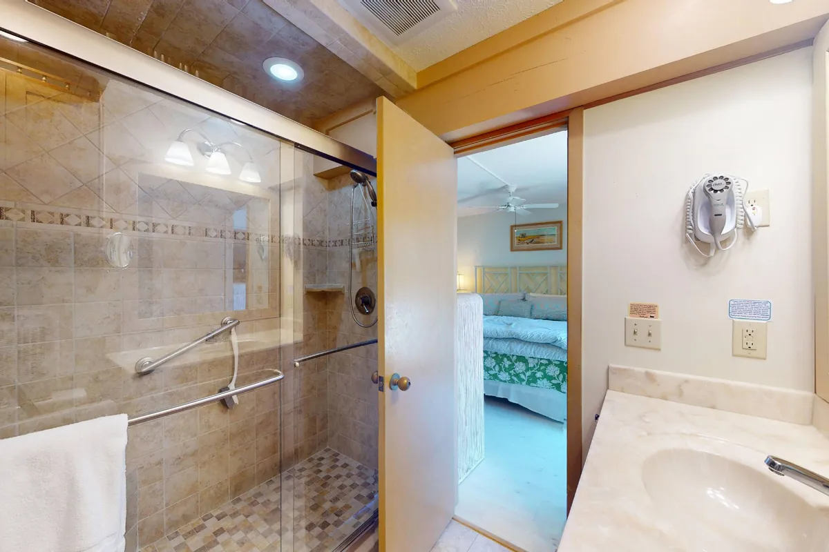 A modern bathroom with a glass shower enclosure, marble countertop, and decorative towel, offering a spa-like atmosphere for guests to refresh.